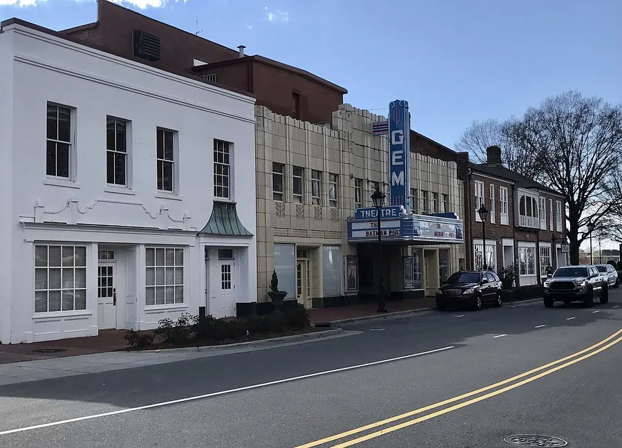 The Gem Theatre in Kannapolis with its tall blue GEM sign and marquee, between a white two-story storefront and brick buildings